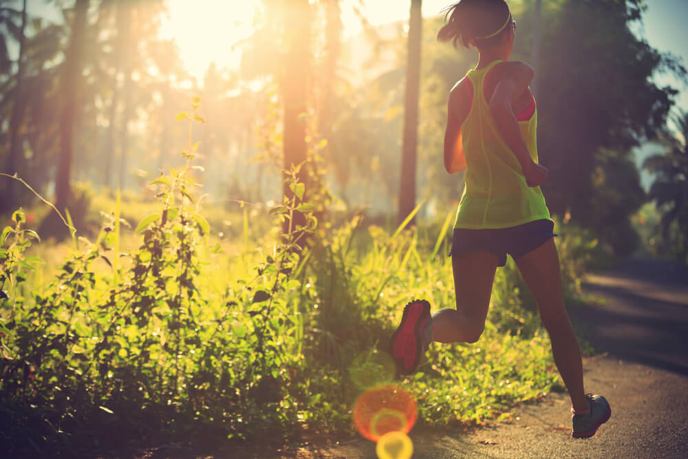Woman running at sunrise in a wooded park