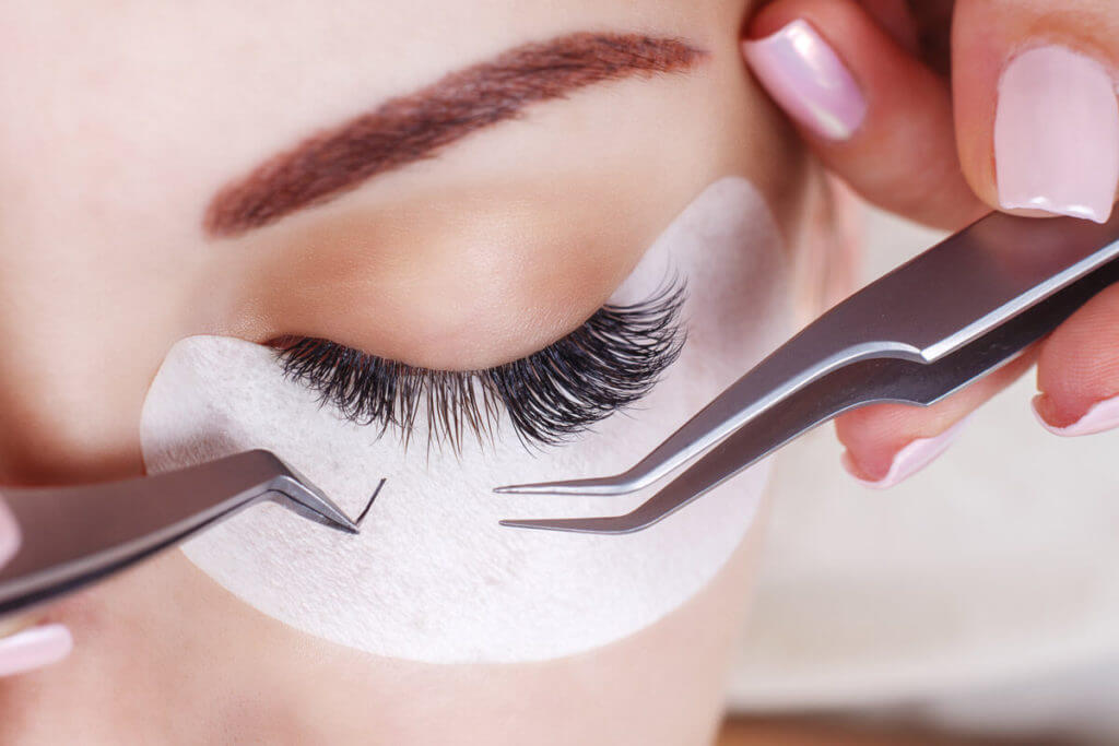 Tweezers near a woman's eyelashes