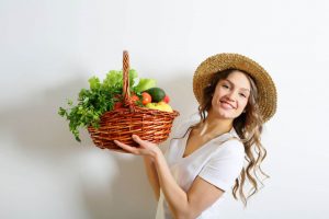 Woman holding large basket of colorful vegetables