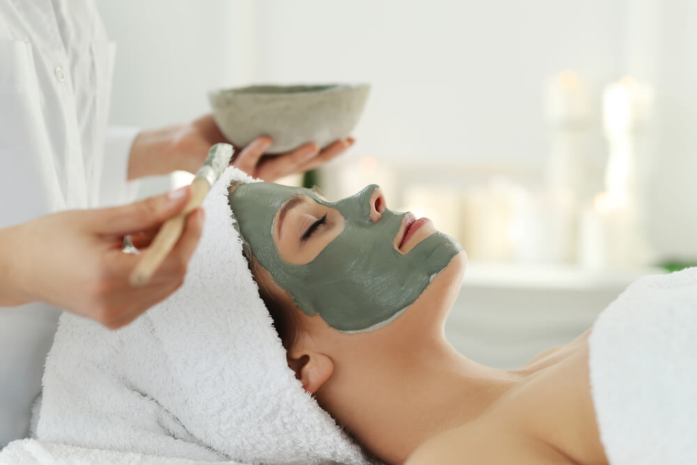 Woman receiving spa facial treatment with green color