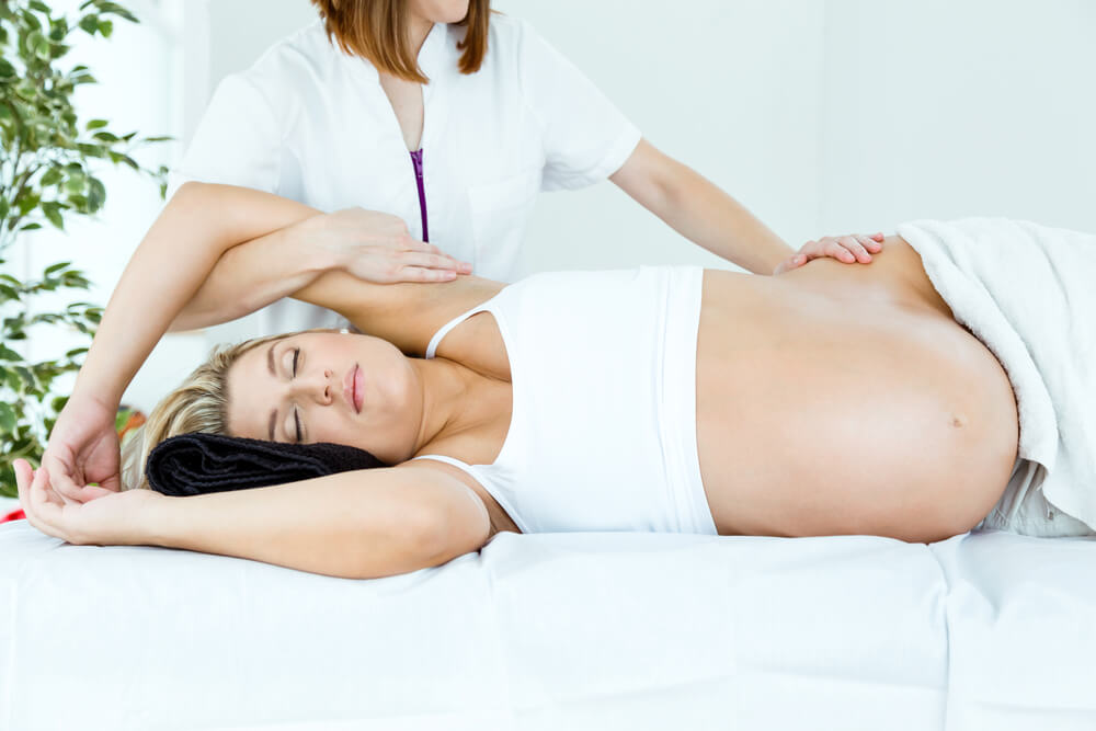 Pregnant woman laying on her side receiving a massage