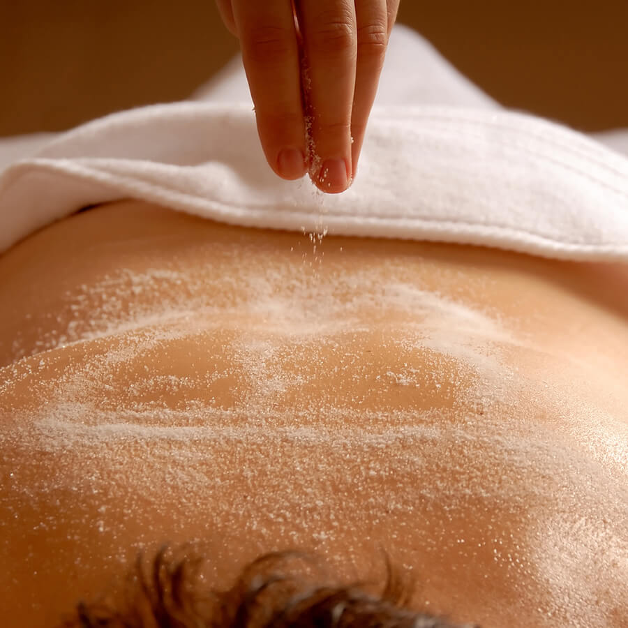 Woman having coconut hydrating and exfoliating body treatment on her back