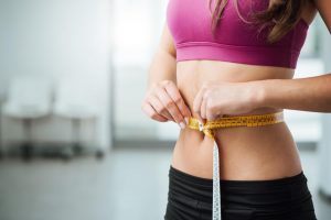 woman losing weight and measuring waistline