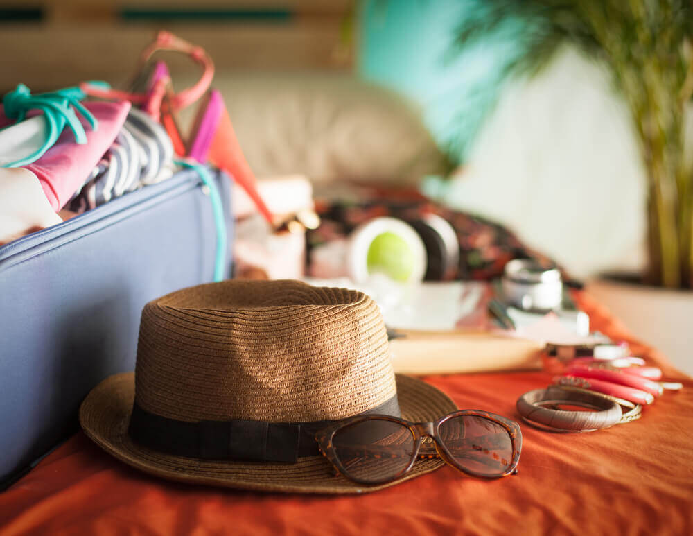 A suitcase with hat, sunglasses, and other items for a vacation